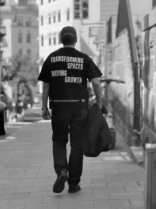 Person i svart t-shirt med trycket Transforming Spaces Driving Growth på ryggen